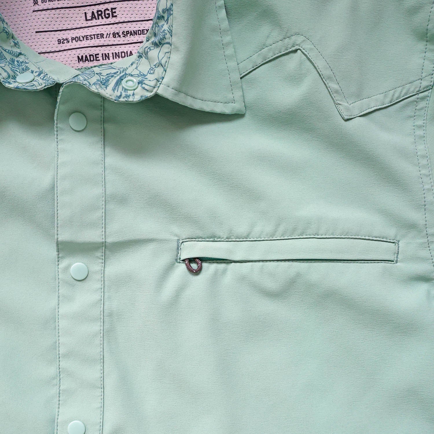 Close-up of a light green/cenote  button down shirt with a sea floor doodle lining collar and chest pocket 