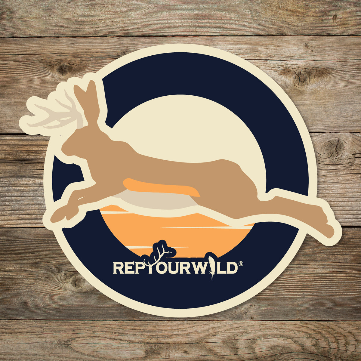 Round sticker dark blue with orange sky in the middle Jumping Jackalope across the center with small rep your wild across the bottom