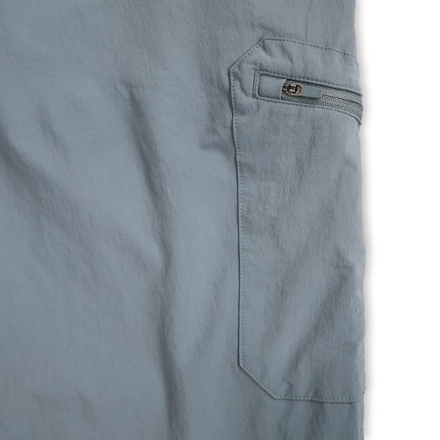Close-up of a light blue zipper pocket on a piece of clothing with a white background