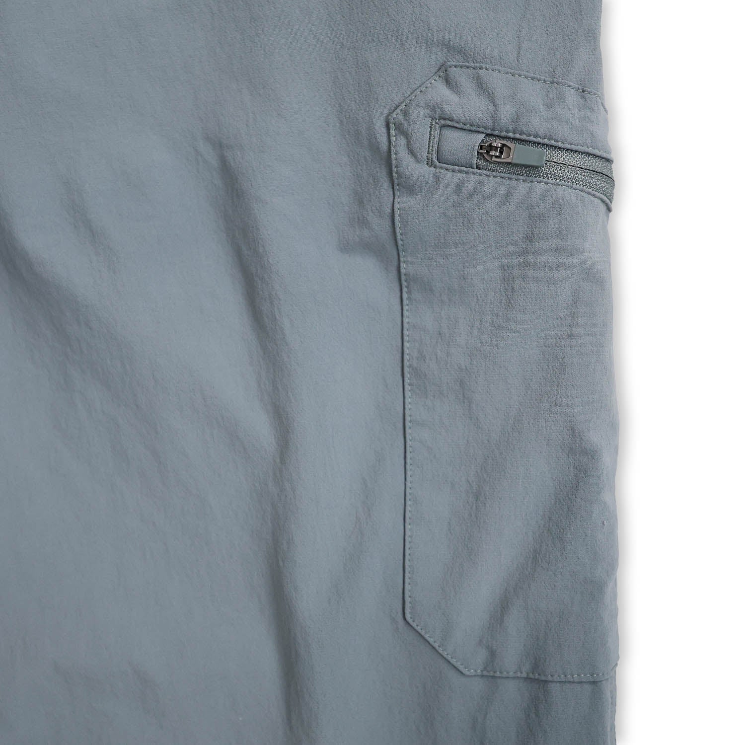 Close-up of a light blue zipper pocket on a piece of clothing with a white background