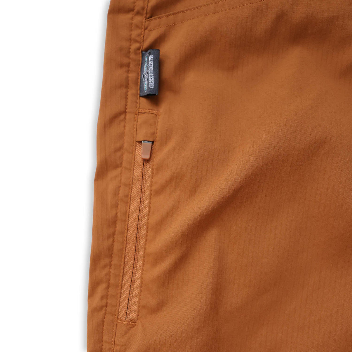 Close-up of teak pants with a brand label on a white background