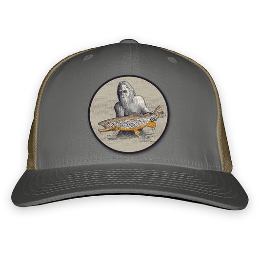 Gray front and tan mesh back with a patch on the front showing sasquatch holding a fish