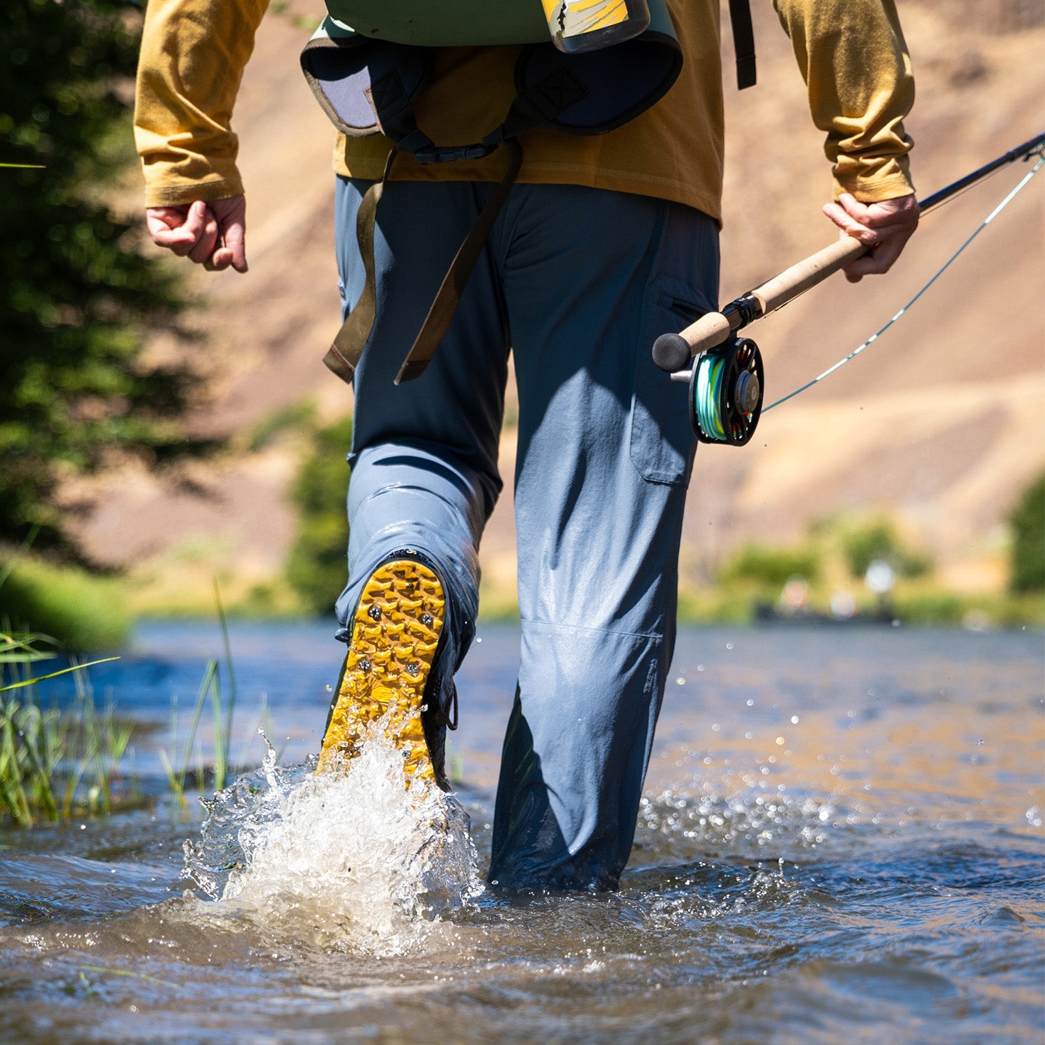 MAn walking though water carrying a fishing rod