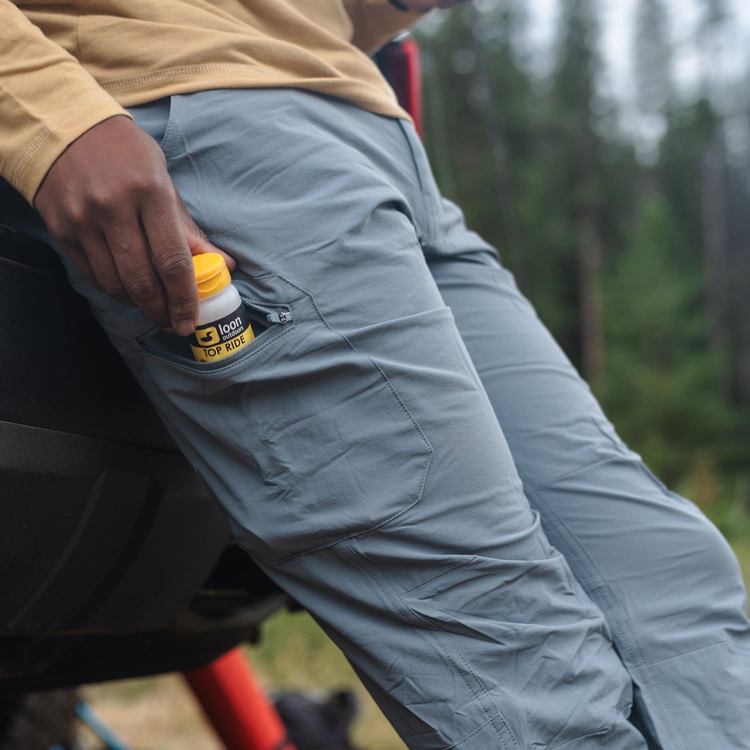 Man putting a container and side pocket of roaring fork pants
