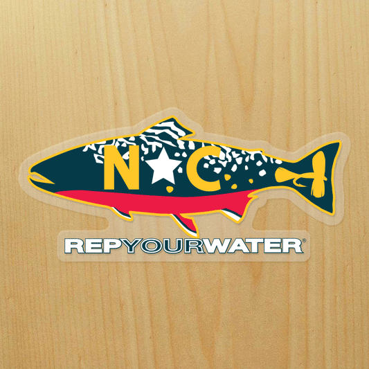 A wood background has a sticker on it that is a brook trout with NC in the middle of it and a fly in the tail.  It reads RepYourWater underneath the trout